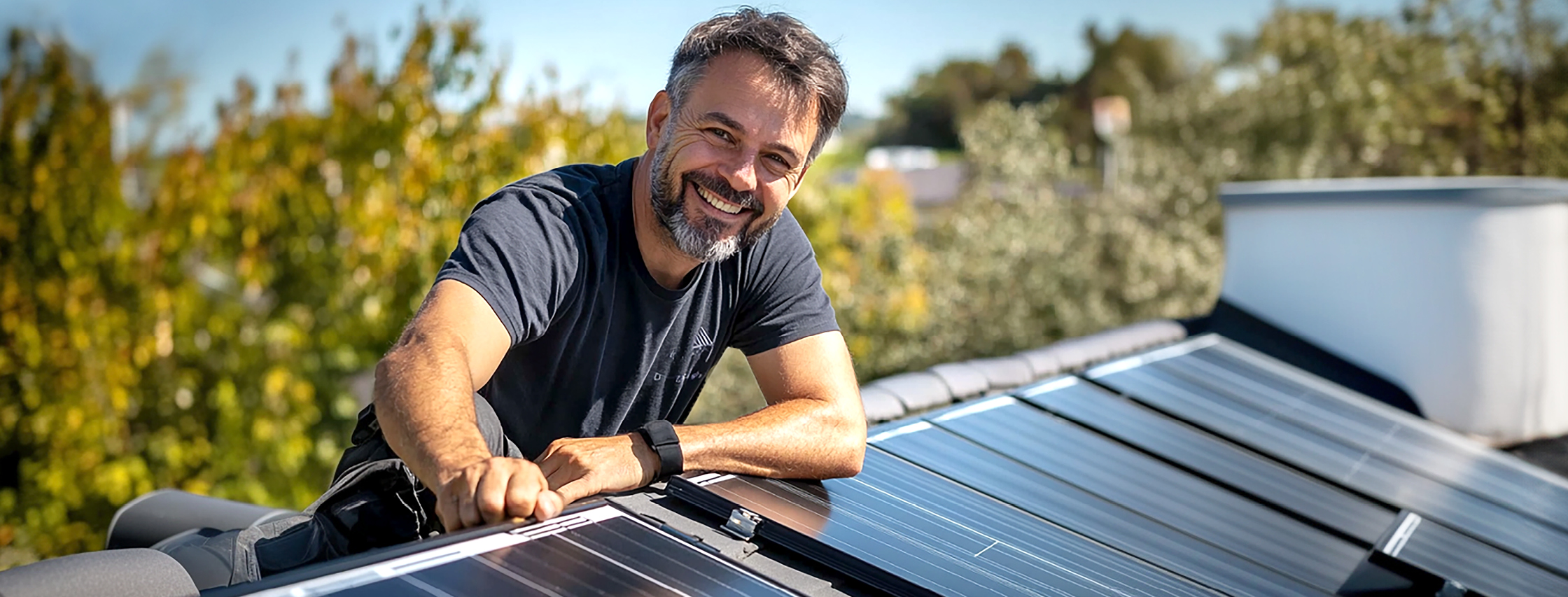 Mann mit Solaranlage, er freut sich weil er mit seiner neuen PV-Anlage doppelt Stromkosten sparen kann