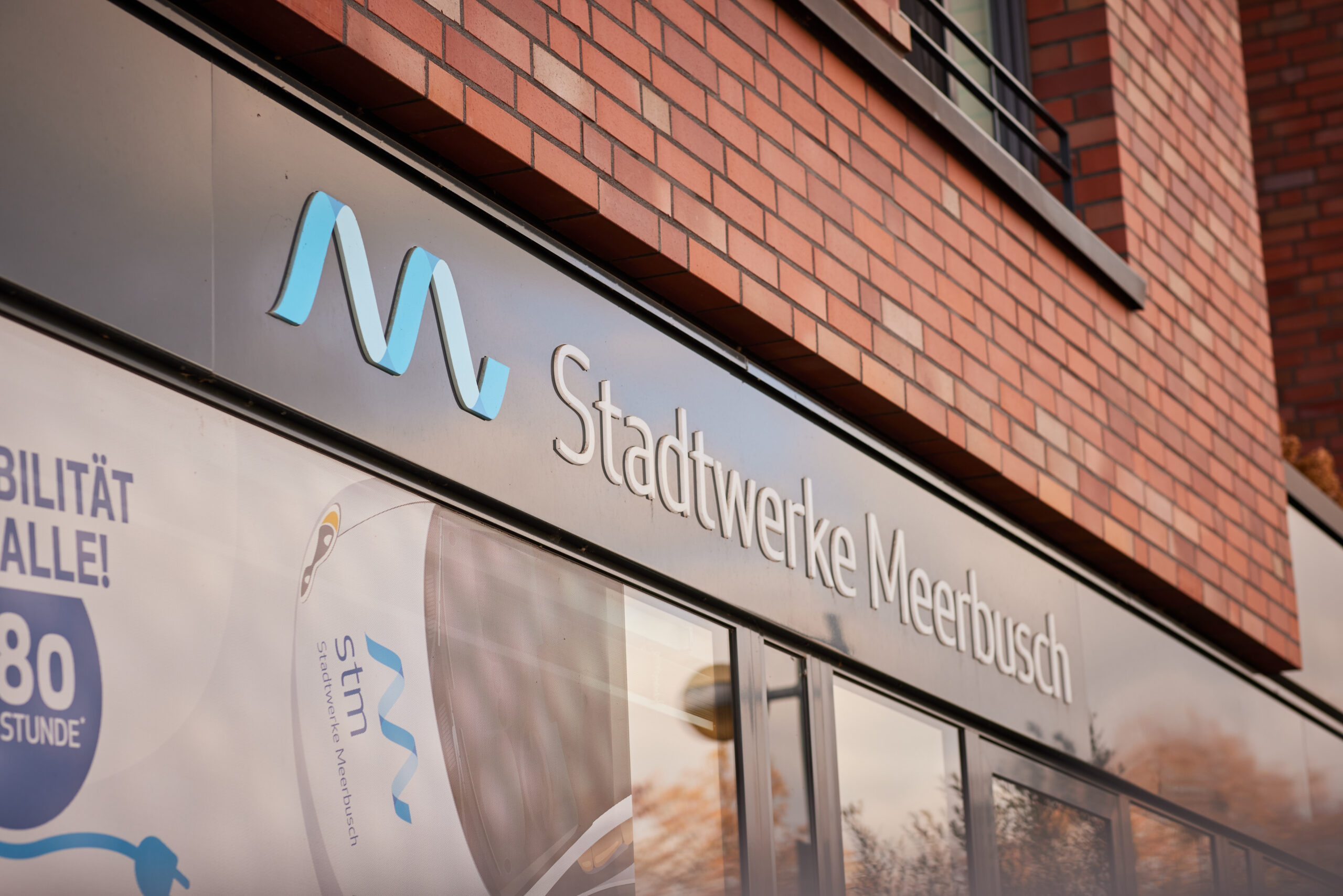 Eingangsbereich der Stadtwerke Meerbusch mit Logo und Schriftzug an der Gebäudefassade.