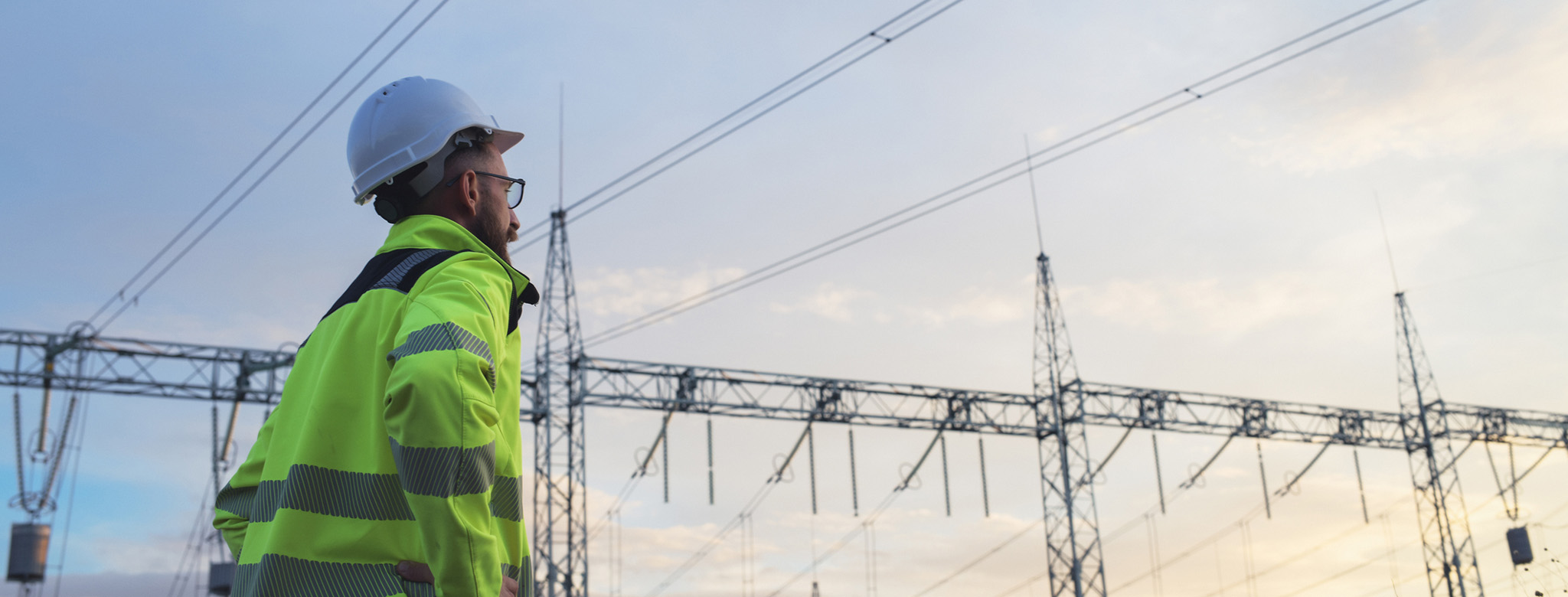 Netzmonteur bei der Arbeit auf einem Umspannwerk mit Schutzkleidung und Helm