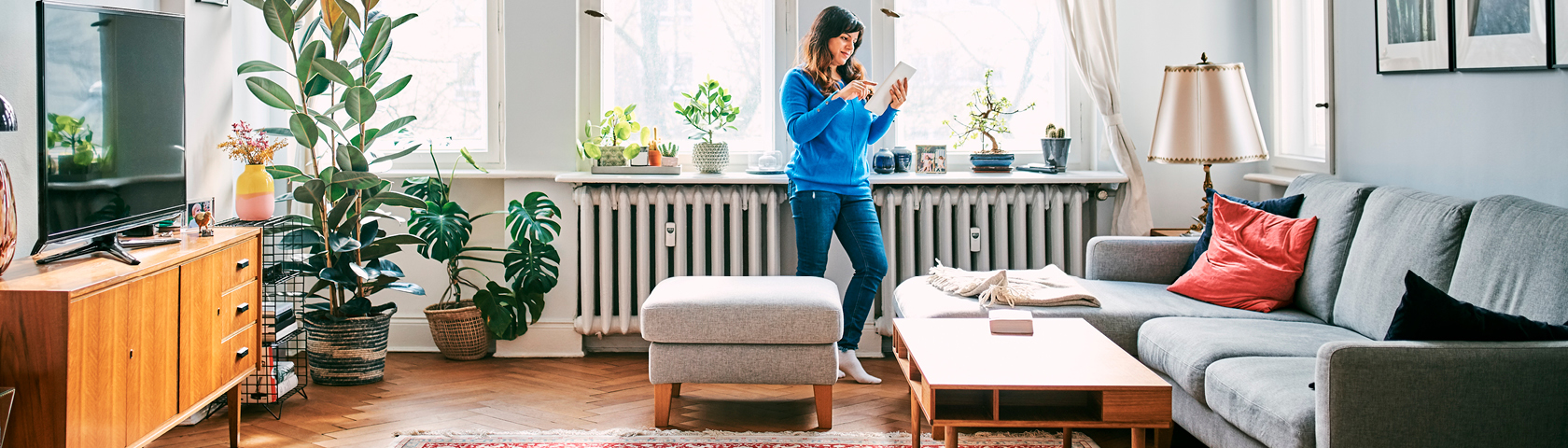Frau sitzt auf dem Sofa und prüft ihre Gaspreise mit dem Tablet