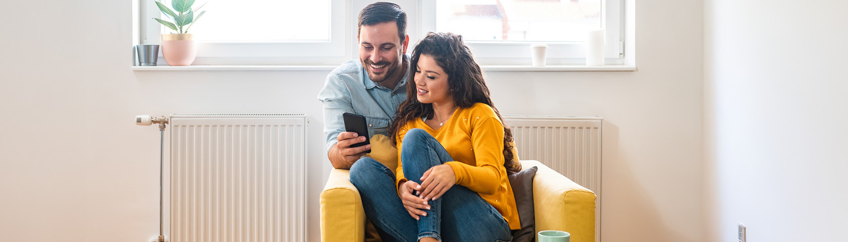 Paar auf Sofa liest am Smartphone Infos zum CO2-Preis beim Gas.