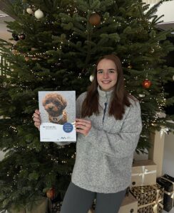 Person hält Familienkalender mit Tiermotiven vor großem Weihnachtsbaum bei Stadtwerke Meerbusch