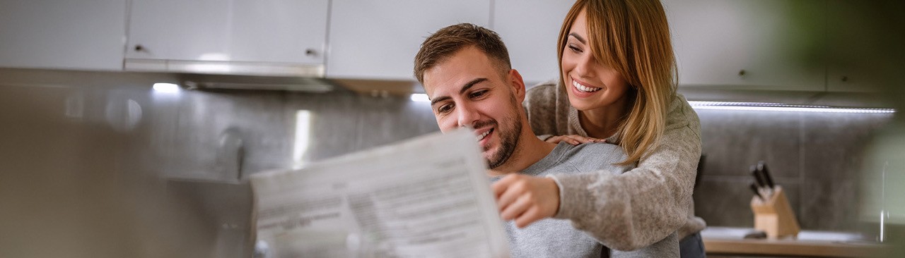 Paar liest zusammen Zeitung in moderner Küchenumgebung