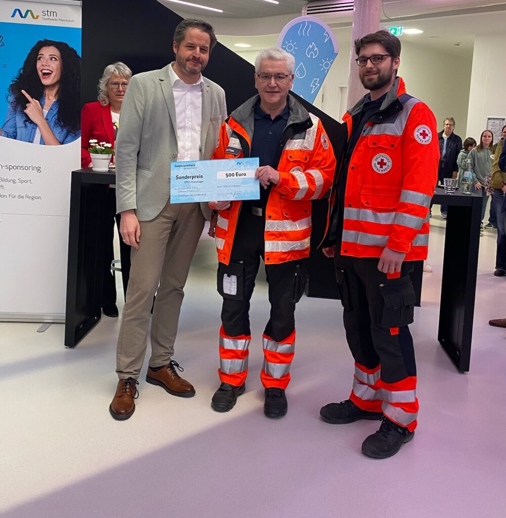 Mitglieder eines Rettungsteams präsentieren symbolischen Scheck bei Preisverleihung